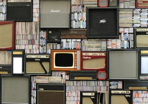 A wall of vintage speakers and TVs surrounded by books and records in a creative display.
