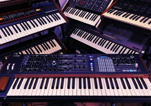 Explore a collection of vintage and modern electronic synthesizers in a studio setting. Perfect for music production enthusiasts.